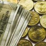 round gold-colored rupee coins and banknotes